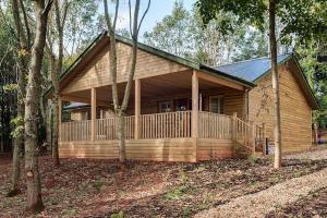 a log cabin with a porch in the woods at Willow Lodge, South View Lodges, Exeter in Exeter