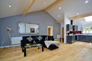 a living room with a black couch and a kitchen at Cedar Lodge, South View Lodges, Exeter in Exeter