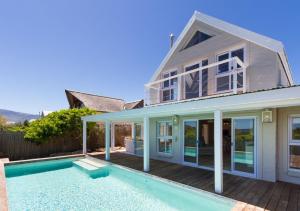 a house with a swimming pool in front of a house at Fin Whale Beach House in Kommetjie