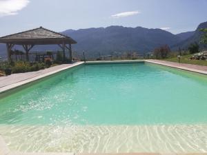 a swimming pool with blue water and a gazebo at LA GRANGE BONAL in Villette