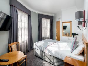 a hotel room with a bed and a table at OYO Townhouse New England, London Victoria in London