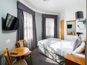 a hotel room with a bed and a table and a tv at OYO Townhouse New England, London Victoria in London +62 photos