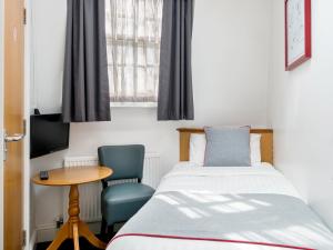 a bedroom with a bed and a table and a window at OYO Townhouse New England, London Victoria in London