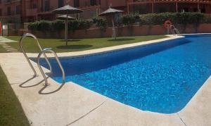 a swimming pool with blue water and an umbrella at Sotogrande - SotoLUX in Sotogrande