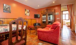 a living room with orange walls and a bed and chairs at Apartamentos Rurales Villa de Sain Cudillero in Cudillero