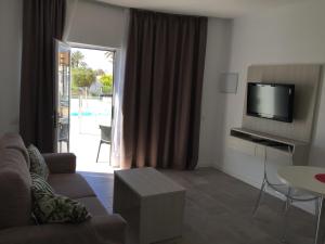 a living room with a couch and a tv at Bungalows Islas Paraiso in Playa del Ingles