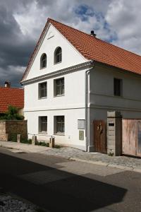 un bâtiment blanc avec un toit rouge dans une rue dans l'établissement Ubytování na statku, à Vědomice