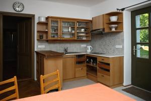 uma cozinha com armários de madeira, uma mesa e um relógio em Ubytování na statku em Vědomice