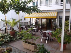 un patio extérieur avec des tables, des chaises et des arbres dans l'établissement Hotel Simeon, à Tossa de Mar