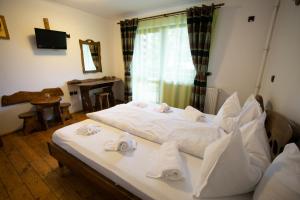 ein Schlafzimmer mit einem großen weißen Bett mit Handtüchern darauf in der Unterkunft Pensiunile Zori de Zi si Apus de Soare in Beliş