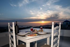 a table with food and drinks on a balcony with the sunset at Labyrinth Traditional Houses in Pyrgos