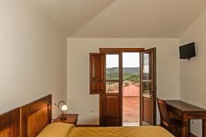 a bedroom with a bed and a view of a balcony at Hotel Funtana Ena in Loceri