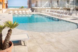 - une piscine avec des chaises et un palmier dans un bâtiment dans l'établissement Hotel Villa Maria, à Caorle