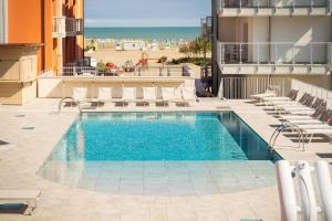 a swimming pool with chairs next to a building at Hotel Villa Maria in Caorle