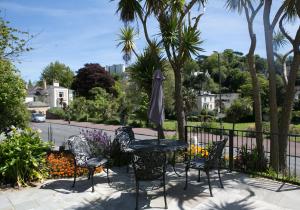 een patio met een tafel en stoelen en een parasol bij Harbour Heights Guest House in Torquay