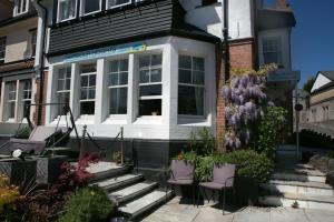 een huis met twee stoelen en bloemen ervoor bij Harbour Heights Guest House in Torquay