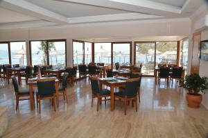 a dining room with tables and chairs and windows at Club Marma Hotel in Akyarlar
