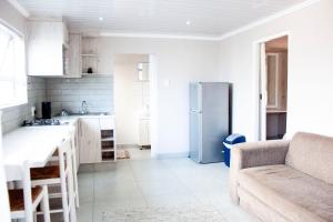 a white kitchen with a couch and a refrigerator at Kelzane Self-Catering in Gonubie