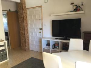 een woonkamer met een televisie en een tafel met stoelen bij Apartman Dénia in Denia