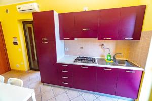 una cocina con armarios morados y fregadero en Villa Mapa - Appartamenti vicino al mare, en Vieste