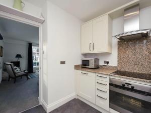 uma cozinha com armários brancos e um micro-ondas em House On The Hill em Framlingham