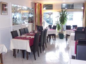 uma sala de jantar com mesas brancas e cadeiras pretas em Hôtel Du Stade em Dijon