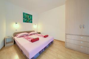 a bedroom with a bed with pink sheets and pink pillows at Holiday Home Traum in Krk