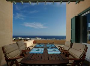 a wooden table and chairs on a balcony with a view at Villa Rosa-Maria in Tinos Town