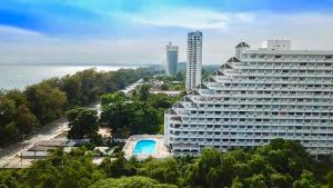 a large building with a pool in front of the ocean at Rayong Condochain by Rainbow in Ban Phe