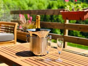 een fles champagne in een emmer op een tafel met twee glazen bij Chalet Eterlou in Mégevette