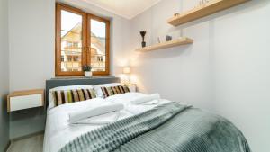 1 dormitorio con 1 cama con sábanas blancas y ventana en Apartamenty Sun & Snow Karpacz Nadrzeczna, en Karpacz
