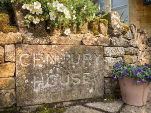 a stone wall with flowers on top of it at Century House in Moreton in Marsh