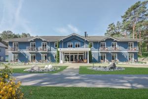 a large blue house with a yard at Upstalsboom Hotel Trassenheide in Trassenheide +25 photos