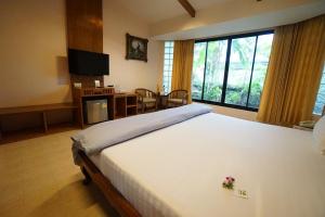 a bedroom with a large bed and a large window at Country Lake View Hotel in Suphan Buri
