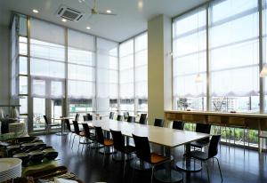 Habitación grande con mesas, sillas y ventanas grandes. en Hotel Inside Numazu Inter, en Numazu
