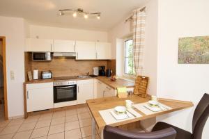 a kitchen with white cabinets and a wooden table at Ferienwohnung Panorama-Blick in Ulmen