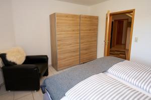 a bedroom with a bed and a chair and a closet at Ferienwohnung Panorama-Blick in Ulmen