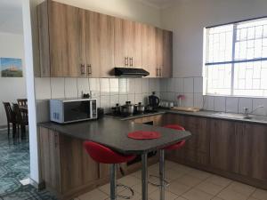 a kitchen with wooden cabinets and a table with red chairs at Home Inn Self-Catering in Windhoek