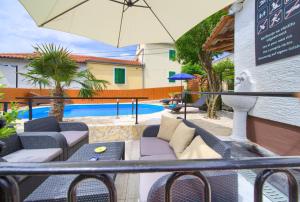 a patio with chairs and an umbrella next to a pool at Holiday Home Traum in Krk