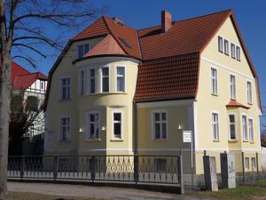 Casa blanca y amarilla con techo marrón en Ferienappartements Rindfleisch, en Stralsund