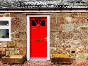 a red door on a brick building with a window at Whiteley’s Cottages studio in Dumbarton