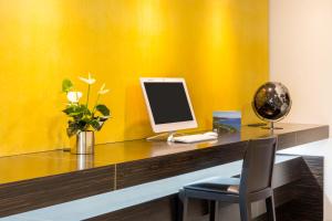 a desk with a computer on a yellow wall at Best Western Hôtel Journel Antibes Juan-les-Pins in Antibes
