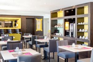 a dining room with tables and chairs and a kitchen at Best Western Hôtel Journel Antibes Juan-les-Pins in Antibes