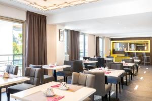a dining room with tables and chairs and windows at Best Western Hôtel Journel Antibes Juan-les-Pins in Antibes