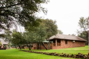 a brick building with a grass yard and trees at Elgro River Lodge in Potchefstroom