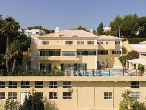 Estoril Luxury Suites & Spa - Cascais في استوريل: مبنى أصفر كبير مع أشجار في الخلفية