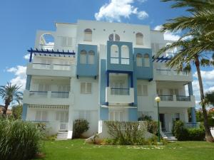 a white and blue building with palm trees in front at CALA BLANCA in Denia