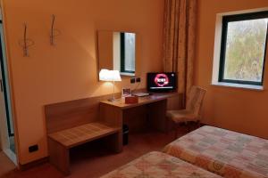 a hotel room with a desk with a television and a bed at Hotel Romanisio in Fossano