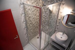 a bathroom with a shower with a sink and a mirror at Hostel Boje in Livno