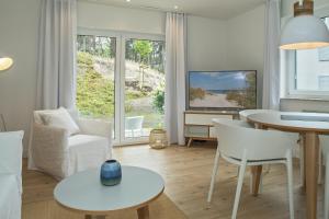 a living room with white furniture and a tv at Upstalsboom Apartments Trassenheide in Trassenheide